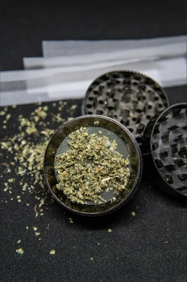 A good 4-piece cannabis grinder sitting open on a desk with fresh flower ready for vaping.